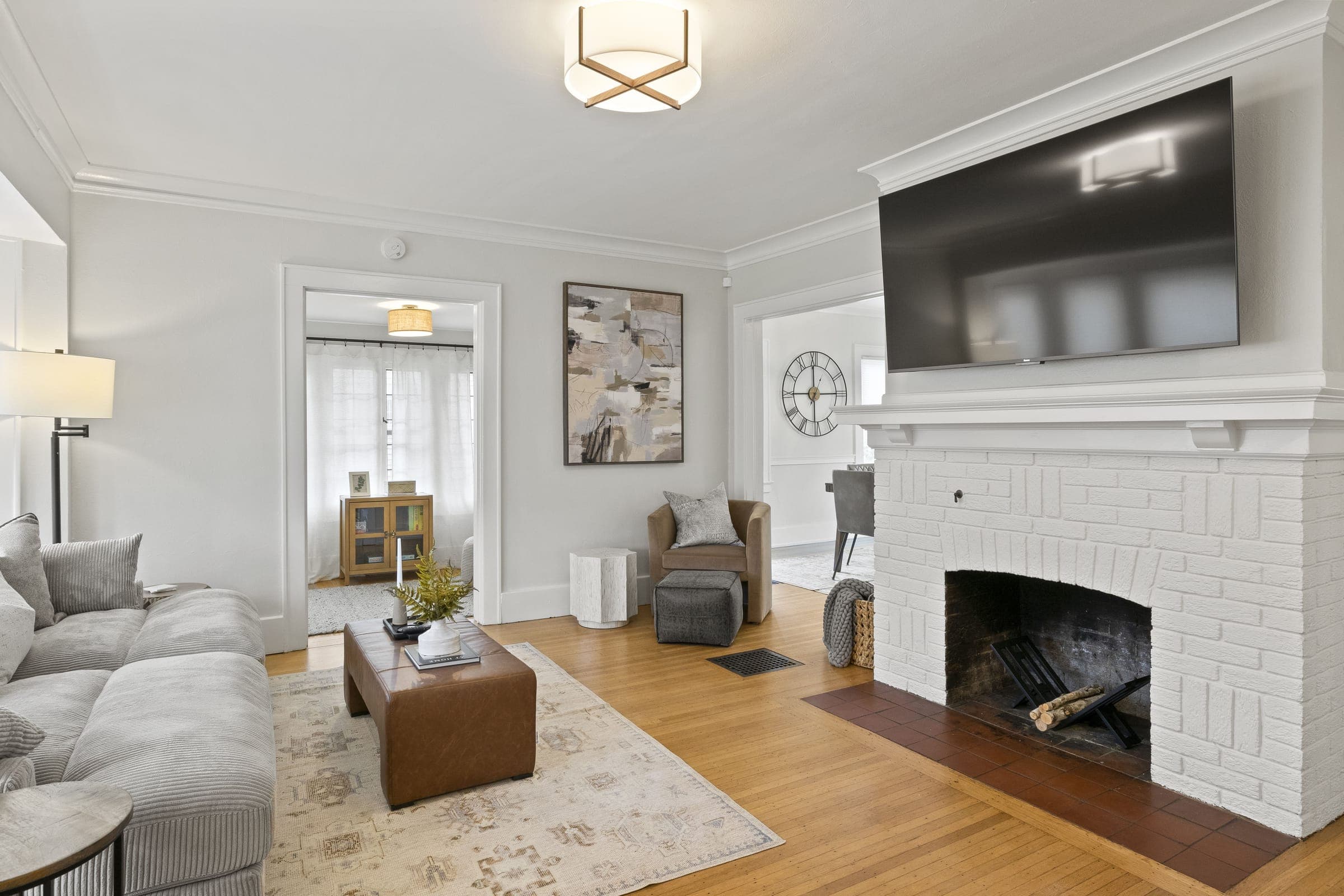 Living room with a white brick fireplace, sectional sofa and wall-mounted TV