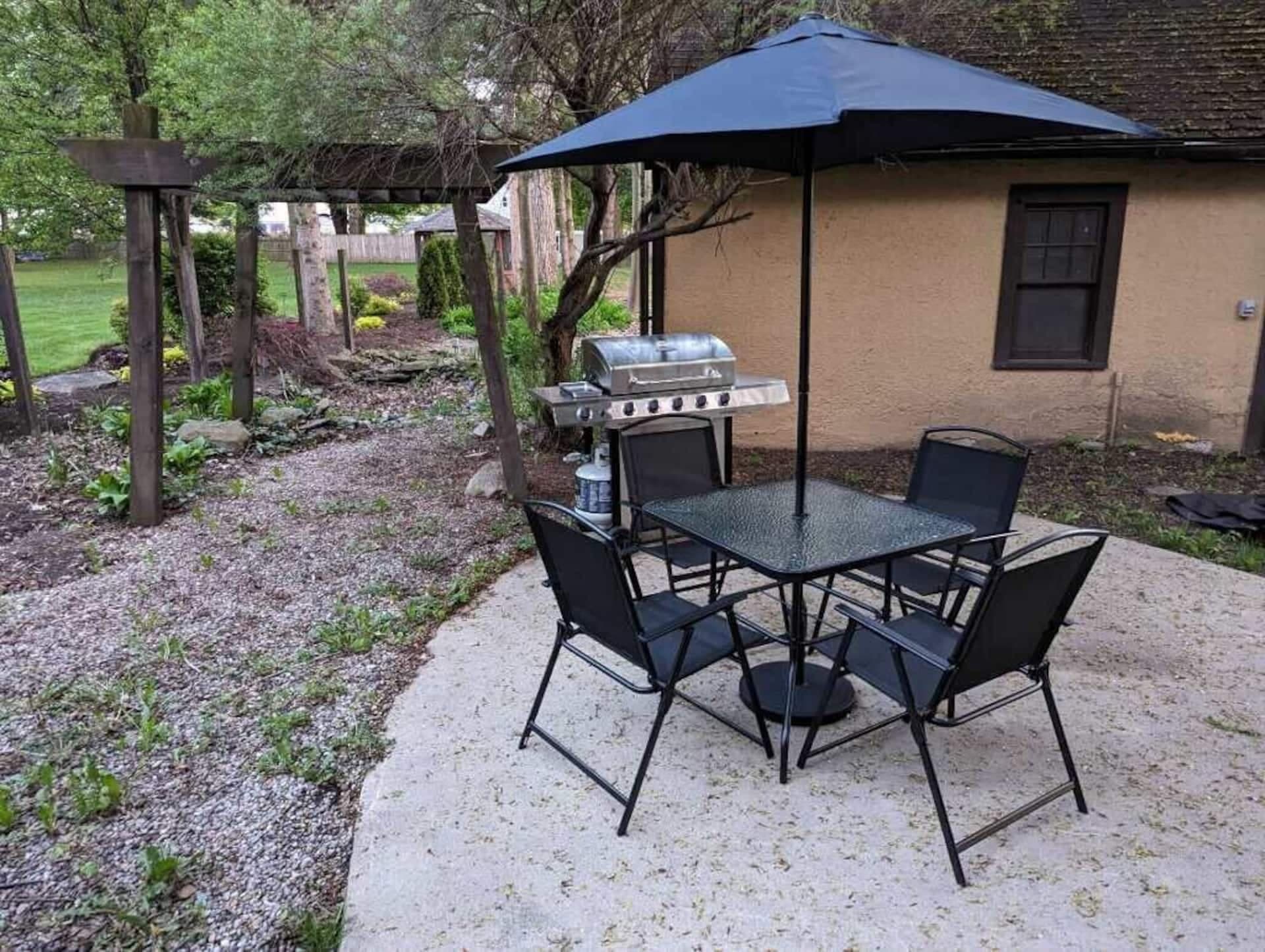 Backyard patio with an umbrella table and grill