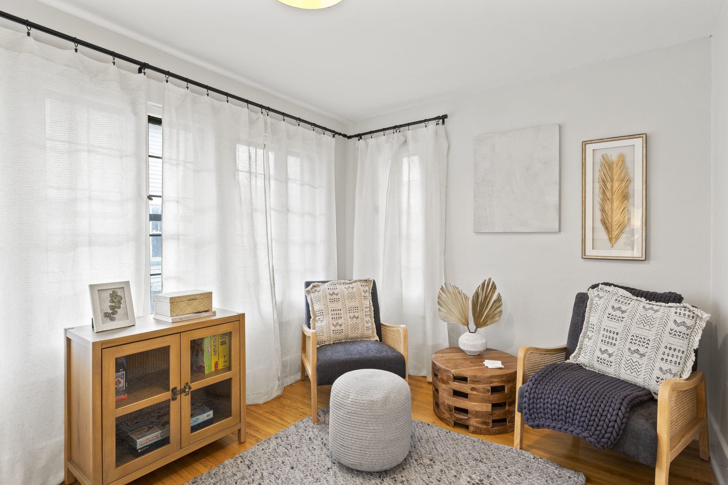 Sunroom with sheer curtains, armchairs and a cabinet